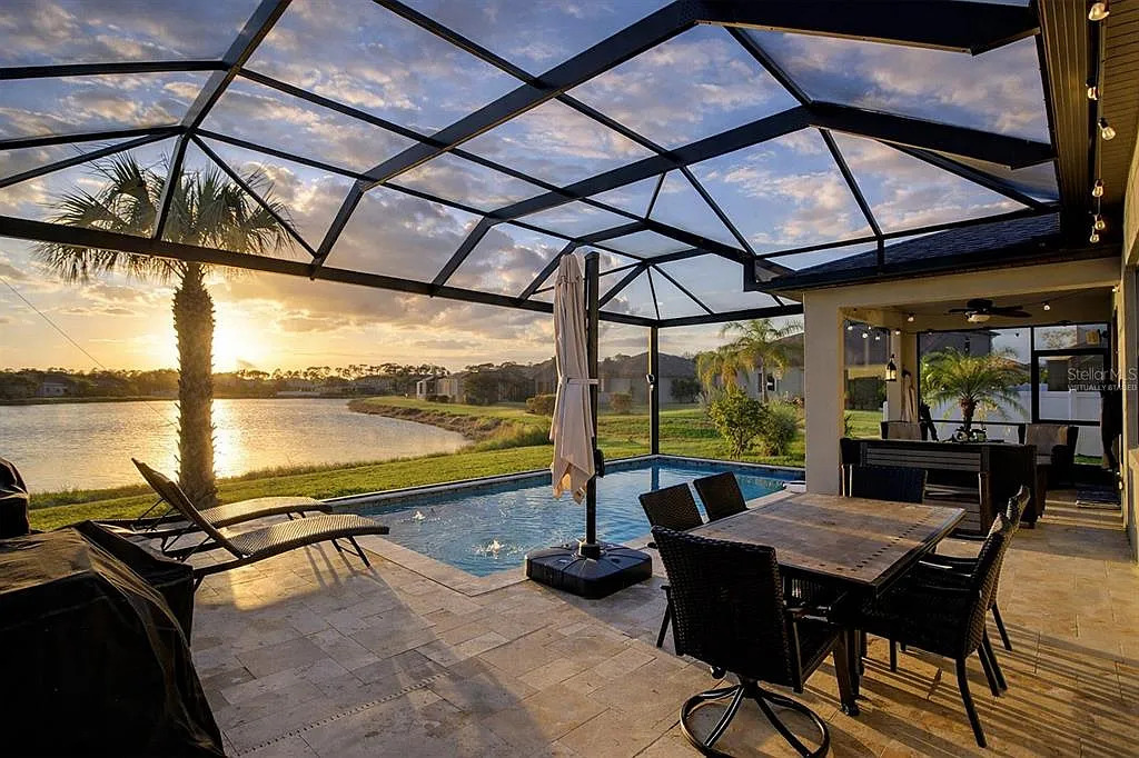 Florida home with a screened pool overlooking a lake at sunset